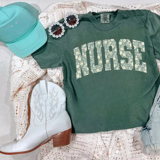 Moss Comfort Colors tee flat lay with floral NURSE varsity arch letter design in cream and green
