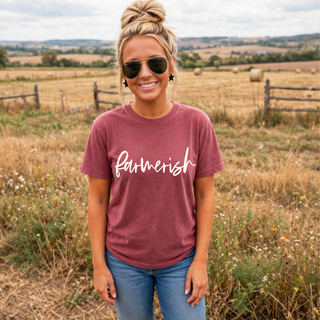 Woman wearing crimson farmerish graphic tee with script lettering in a farm field