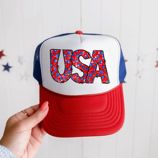 Hand holding white rich red true royal trucker hat with faux glitter usa stars bold red and blue star filled letter design
