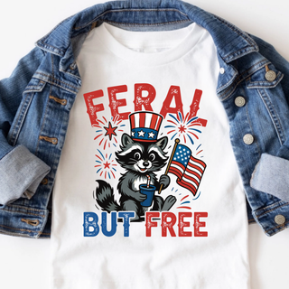 White youth tee with feral but free fireworks patriotic raccoon graphic, styled with a denim jacket on white background
