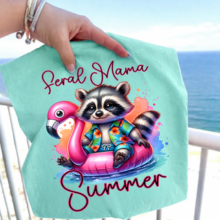 Chalky mint Comfort Colors tee held up at the beach with feral mama summer raccoon flamingo float graphic
