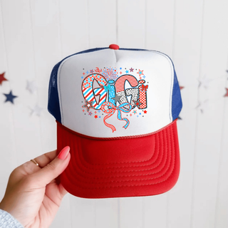 Hand holding white rich red true royal trucker hat with firecracker doodle gigi patterned letters red white blue stars bows
