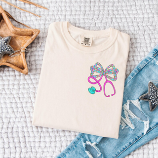 Floral Bow Stethoscope Pocket Graphic Top in ivory with colorful floral bow and pink stethoscope pocket design
