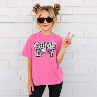 Girl wearing Game Day Volleyball Dalmatian Print top in pink with black and white spotted lettering and net graphic