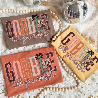 Gobble Till You Wobble Tee - front view, turkey and floral graphic with GOBBLE TILL YOU WOBBLE wordmark on a Comfort Colors tee