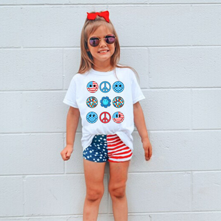 Little girl wearing white tee with groovy peace love america retro icon grid peace signs smileys disco balls red white blue
