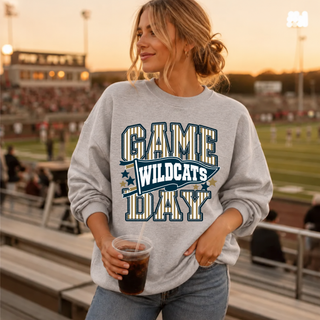 Model wearing heather grey Hayden Wildcats Game Day crewneck with navy and gold pinstripe lettering and WILDCATS pennant, at a football game