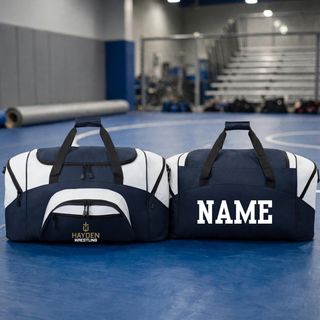 Navy and white colorblock duffel bag shown on a wrestling mat, with the Hayden Wrestling Cross Crest on the front pocket and a name on the back.