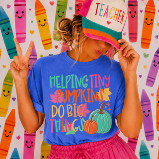 flo blue adult graphic tee with helping tiny pumpkins do big things teacher design, model wearing teacher hat with crayon background
