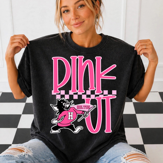 Woman wearing a black tee with pink PINK OUT bubble lettering, a pink checkered stripe, and a cartoon wildcat mascot in a pink Holton jersey carrying a Holton pennant