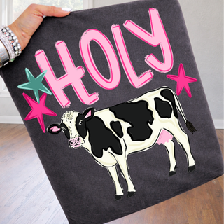 Pepper Comfort Colors tee held up with bold holy brushstroke text and black and white cow graphic
