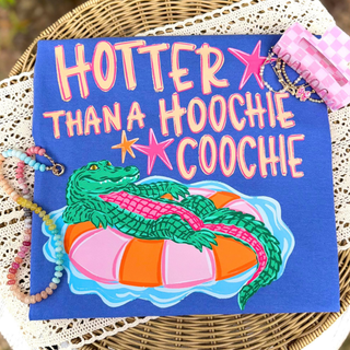 Folded flo blue Comfort Colors tee with colorful alligator on pool float and Hotter Than a Hoochie Coochie graphic
