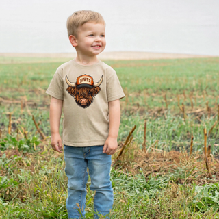 Howdy Highland Cow Top graphic tee on toddler boy in a farm field