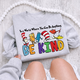 Sport grey crewneck flat lay with In a World Where You Can Be Anything BE KIND colorful storybook character design
