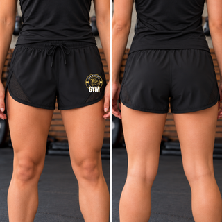 Woman wearing black athletic shorts with the Iron Warriors Gym lion crest low on the left leg, front and back views