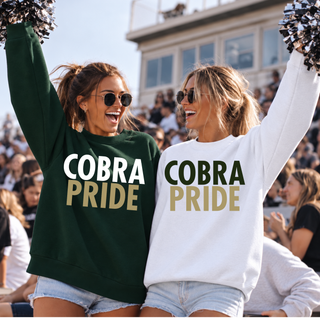 Two women wearing Jackson Heights Cobras Cobra Pride crewneck sweatshirts in forest green and white at a football game