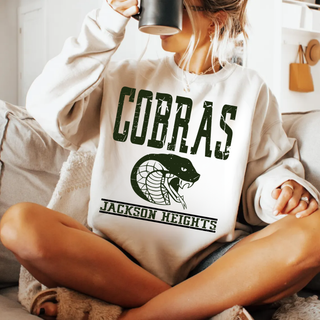 Jackson Heights Cobras Distressed Mascot Banner Top in white, model wearing crewneck while holding a mug