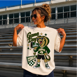 Woman wearing cream Jackson Heights Cobras Game Day Mascot Top with cartoon cobra mascot holding a Go Cobras megaphone and Cobras pennant flag