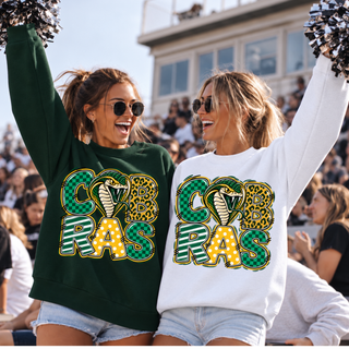Jackson Heights Cobras Print Block Top, stacked COBRAS graphic in green and gold print-block lettering with a cobra head forming the O, on grey and white crewneck sweatshirts