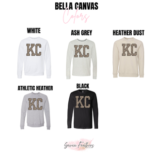 Bella Canvas crewneck sweatshirts and long sleeve tees in white, ash grey, heather dust, athletic heather, and black with KC lettering in leopard print and black outline