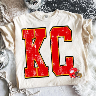 ivory adult top with distressed red gold kc lettering and helmet graphic, disco ball styled flat lay
