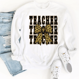 White crewneck sweatshirt with stacked leopard TEACHER text and leopard bow, styled with jeans and sneakers
