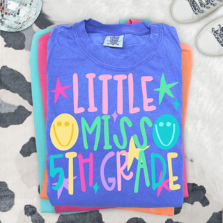 Little Miss 5th Grade graphic tee in blue violet folded with colorful lettering, stars, and smiley faces
