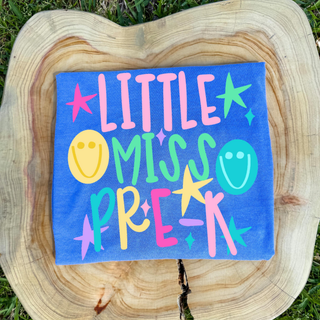 Little Miss Pre-K graphic tee in flo blue with colorful lettering, stars, and smiley faces
