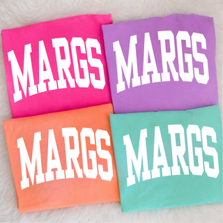 Neon pink, neon violet, neon cantaloupe, and chalky mint Comfort Colors tees with Margs varsity arch lettering flat lay