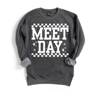 Dark grey crewneck sweatshirt laid flat with MEET DAY bold checkered varsity graphic and sparkle star accents
