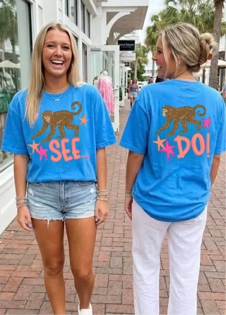 Two women wearing the Monkey See Monkey Do Graphic Tee in flo blue showing front SEE and back DO monkey star design