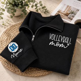 Black quarter-zip styled flat lay with VOLLEYBALL mom lettering on the chest and a volleyball graphic with custom number and name on the sleeve