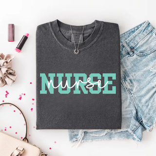 Pepper Comfort Colors tee with teal block Nurse design and white script overlay, folded flat lay