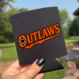 Hand holding a black neoprene Ogden's Outlaws Wrestling bullet hole can koozie with orange western-style Outlaws lettering, a swash tail and a bullet hole in the O