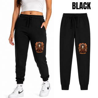 Woman wearing black core fleece joggers with the Ogden's Outlaws Wrestling feathered skull and crossed axes graphic on the lower leg, next to a flat lay
