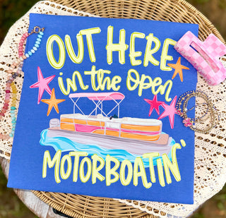 Flo blue tee with OUT HERE IN THE OPEN MOTORBOATIN pontoon boat colorful graphic flat lay front view
