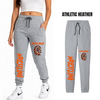 Woman wearing athletic heather grey fleece joggers beside a flat grey pair, with Outlaws and a feathered skull on the thigh and large orange Wrestling lettering down the lower leg