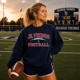 Oversized Jr. Vikings football navy crewneck front with Jr. Vikings football logo, model on Seaman field