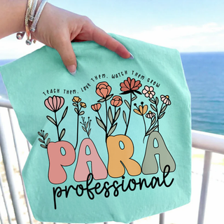 Hand holding chalky mint tee with PARA professional floral design and TEACH THEM LOVE THEM WATCH THEM GROW text
