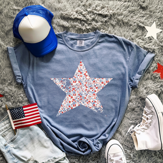 Blue Jean Comfort Colors tee with a large red white and blue floral star graphic styled with denim shorts and sneakers