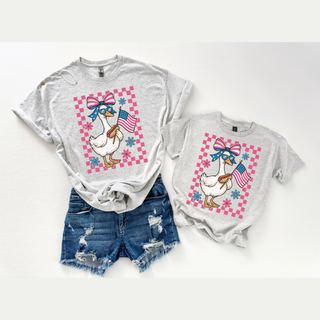 Adult and child athletic heather graphic tops with patriotic goose bow sunglasses American flag pink checkered design laid flat with denim shorts