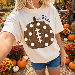 Woman wearing ivory polka dot football pumpkin top with hand painted pumpkin designed like a football
