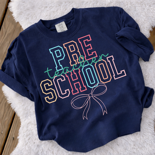 Preschool teacher graphic tee in true navy with colorful varsity letters and bow graphic
