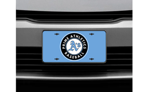 Prime Athletics Baseball circle badge license plate in black and light blue on a Carolina blue background, shown mounted on a vehicle front grille
