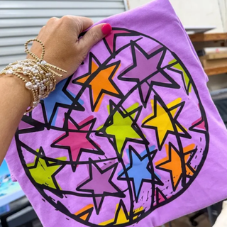 Violet Comfort Colors tee with rainbow multicolor star volleyball graphic held up front view
