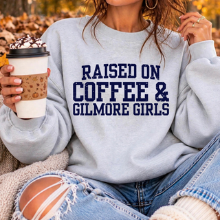 Raised On Coffee varsity-style design in distressed navy lettering on a light blue crewneck sweatshirt