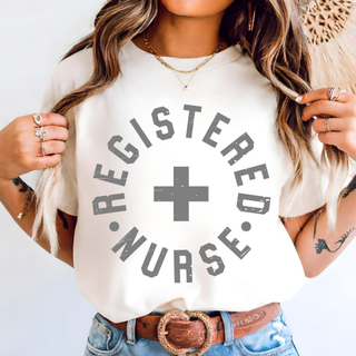 Woman wearing ivory Comfort Colors tee with distressed Registered Nurse circle and cross design