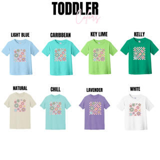 Toddler tees in light blue, caribbean, key lime, kelly, natural, chill, lavender, and white with retro checkered smiley flower design
