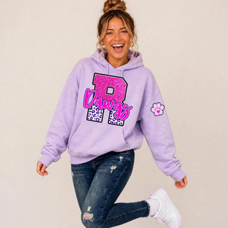 Model wearing a lavender hoodie with a pink faux-glitter R, purple leopard print, Dawgs script, and paw print sleeve accent