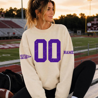 Sand crewneck sweatshirt with distressed purple custom number on the chest, a Panthers pennant flag icon on one sleeve, and a personalized name on the other sleeve